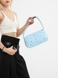Borsa sottobraccio azzurra in ecopelle con borchie argento indossata da una modella