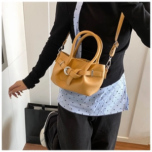 Gros plan d'un sac à main jaune moutarde avec boucle décorative et fine bandoulière en cuir