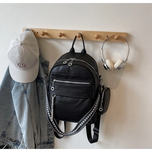 Detail of black lychee grain leather backpack with silver zippers and wide patterned strap