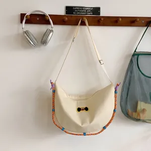 Dettaglio della borsa a mezzaluna in nylon beige con toppa a cucciolo e corda intrecciata