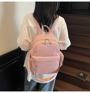Detailed close-up of pink lychee-patterned leather backpack with silver zippers
