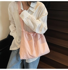 Side view of pink waffle textured tote bag with wide strap on model in natural light