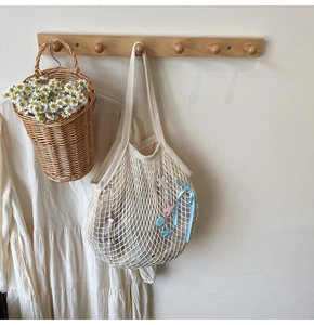 Detail of woven tote bag with star charms and blue bow on a wooden hanger
