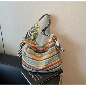Dettaglio della borsa tote in paglia intrecciata colorata con tracolle a righe e margherite