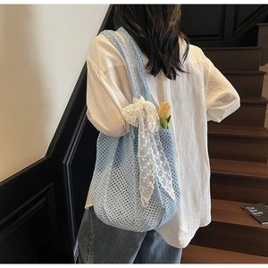 Détail du sac cabas au crochet bleu clair avec nœud en dentelle et décor de tulipe