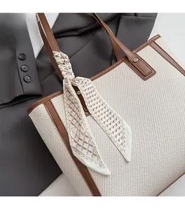 Detail of canvas tote bag with brown leather handles and a geometric silk scarf wrap