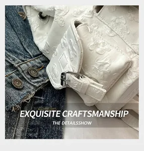 Gros plan sur la texture florale 3D blanche et la boucle métallique du sac