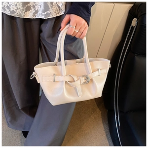 Détail d'un sac seau crème élégant avec boucles décoratives et poignées rondes