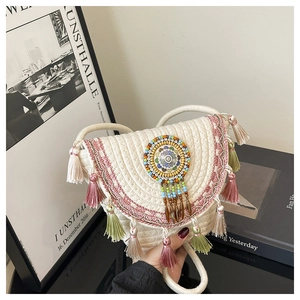 Dettaglio della borsa in paglia boho con nappe colorate e ricami di perline elaborati