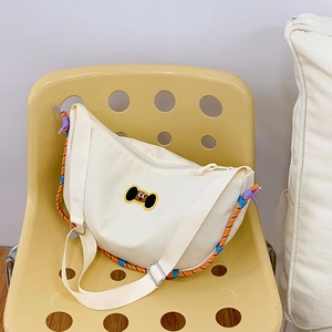 Dettaglio borsa a mezzaluna in nylon crema con toppa a cucciolo e dettagli in corda colorata