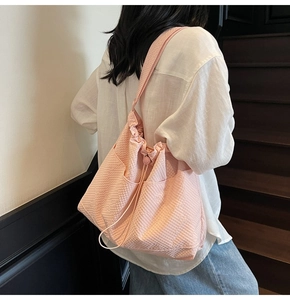 Close-up of pink drawstring bucket bag featuring a fine textured grid pattern and side pockets