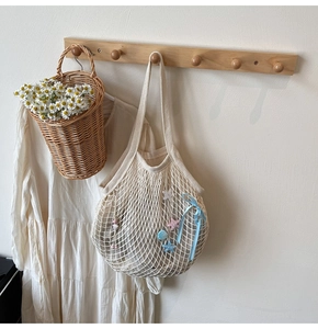 Detail of woven mesh tote bag in cream white featuring a light blue ribbon bow and star charms