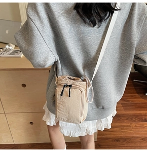 Back view of beige nylon crossbody phone bag with drawstring and front zipper pocket