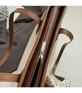 Detail of smooth metal zipper and silver puller on a canvas tote bag with leather trim