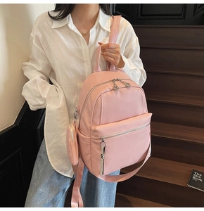 Pink lychee texture backpack with detachable mini pouch on a wooden staircase