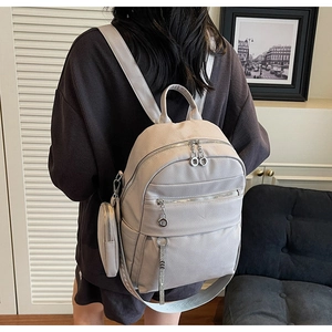 Detail of grey lychee leather backpack with side coin purse and wide fabric shoulder straps