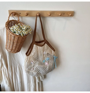 Detail of woven mesh tote bag with blue silk bow and star charms on wooden hook