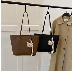 Detailed shot of brown and black pebbled tote bags with teddy bear charms on display