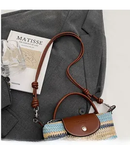 Detail of woven straw bag with blue and yellow stripes and brown leather flap handle