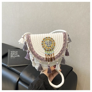 Dettaglio della borsa bohémien in paglia con perline colorate e nappe di cotone