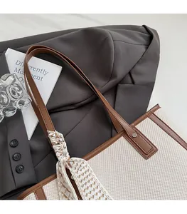 Detail of woven tote bag with brown faux leather straps and decorative silk scarf accessory