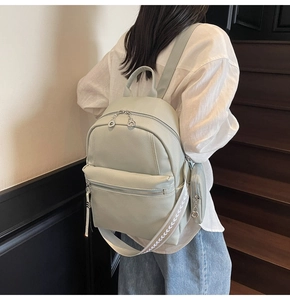 Detail of light green pebbled leather backpack with silver hardware and small coin purse