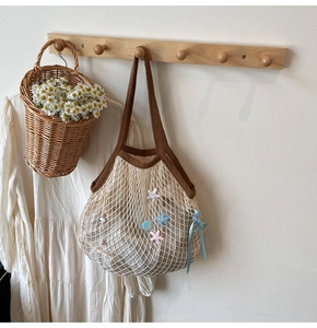Detail of woven tote bag with star shell charms and a blue bow on a wooden hook