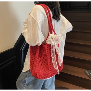 Détail du sac cabas en maille rouge avec un nœud en dentelle blanche sur le crochet