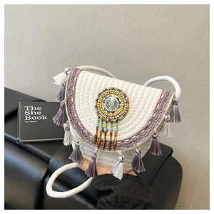 Dettaglio della borsa intrecciata boho con frange viola e ricami di perline colorate