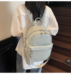 Detail showing mint green faux leather backpack with jacquard strap and silver zippers