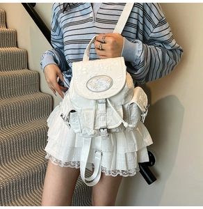 Details des weißen Rucksacks mit floraler Prägung, Metallplakette und Kordelzugverschluss