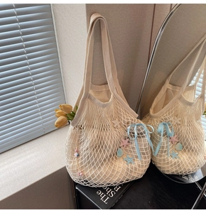Close-up of woven tote bag with blue ribbon bow and starfish shell charms detailing
