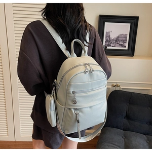 Detail of light blue faux leather backpack with silver ring zippers and mini pouch