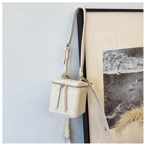 Detailed view of cream textured leather box crossbody bag with silver double zippers