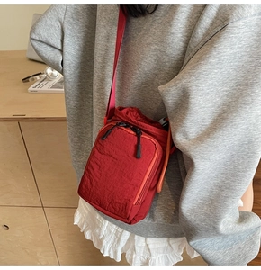 Close-up of red nylon mini bucket bag with drawstring closure and front zipper pocket