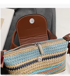 Close-up of woven straw bag with metal zipper, magnetic buckle and brown leather handle