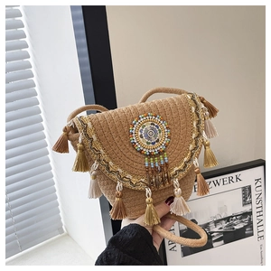 Dettaglio della borsa a secchiello in paglia con lunghe frange e motivi mandala di perline
