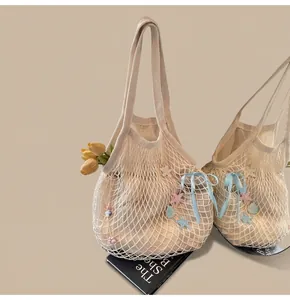 Detail of cream woven tote bag with blue ribbons, star charms and fresh tulips