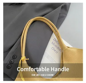 Détail de la poignée du sac fourre-tout en cuir jaune sur costume gris et magazine