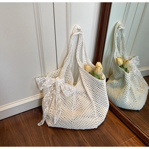Détail du sac cabas en crochet beige avec maille ajourée et nœud en dentelle élégant