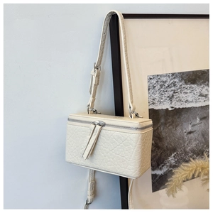 Detailed macro view of off-white vanity case bag with textured grain leather and silver hardware
