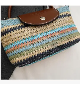 Detail of colorful woven straw bag featuring brown leather flap and metal snap button