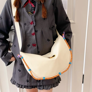 Dettaglio borsa a mezzaluna in nylon crema con corda intrecciata arancione e tracolla