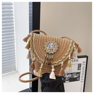 Dettaglio borsa a secchiello in paglia boho con nappe colorate e disco mandala