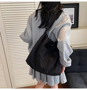 Detailed back view of a large black casual nylon tote bag worn by a model in casual style