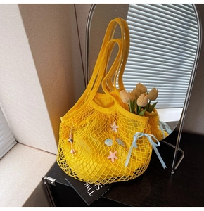 Detail of yellow woven tote bag with sea shells, starfish and light blue silk bow decor