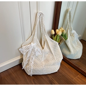 Gros plan d'un sac cabas tissé crème avec motifs ajourés et un grand nœud en dentelle