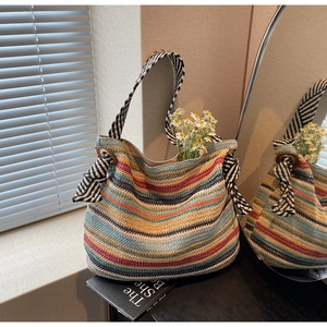 Dettaglio della borsa tote in paglia colorata con strisce arcobaleno e fiocco a righe