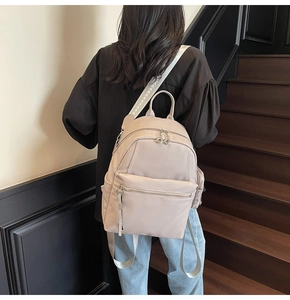 Detail of minimalist cream backpack showing lychee texture and woven shoulder strap