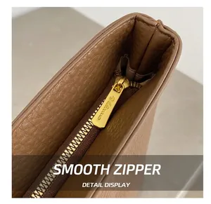 Detailed macro view of smooth gold zipper and pebble leather texture on tote bag